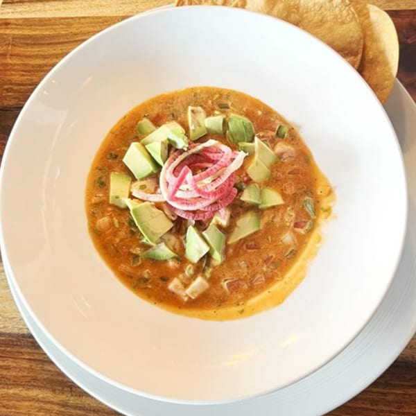 Ofrenda's Mexican ceviche with avocado and pickled red onions in a white bowl with tortilla chips.